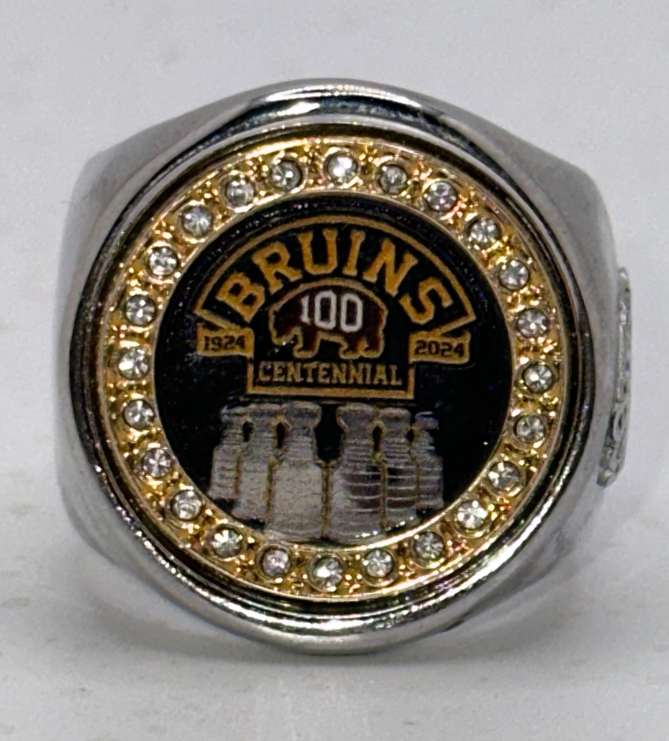 The deCAPitator BRUINS CENTENNIAL 1924 to 2024 ring bottle cap and can tab opener. Sizes 6 to 15 with ring sizer. Made of stainless steel.